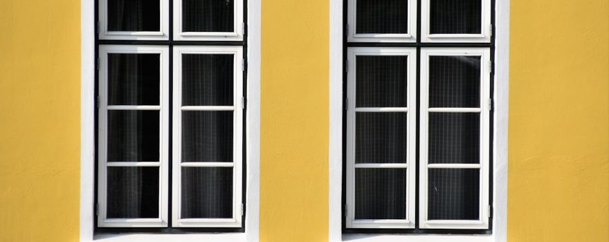 Yellow wall featuring two multiple pane windows. Learn how to insulate old windows