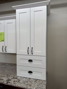 Close-up of tall upper white cabinet with Shaker doors and black hardware