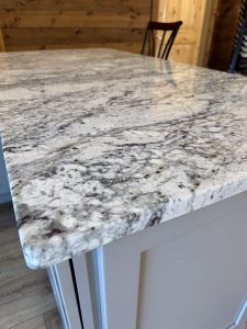 Close-up view of African Rainbow Granite countertop on Stone Harbor Gray kitchen island display