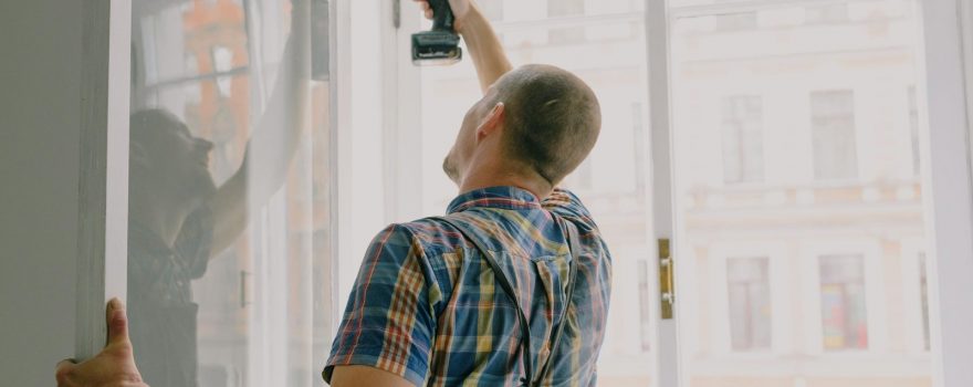 Installer securing a replacement window with a drill.