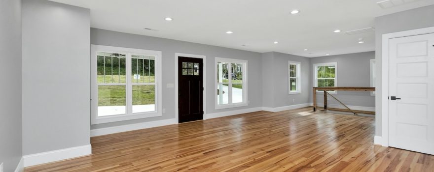 Suggested alt text: Bright empty room with glossy refinished hardwood floors and large windows